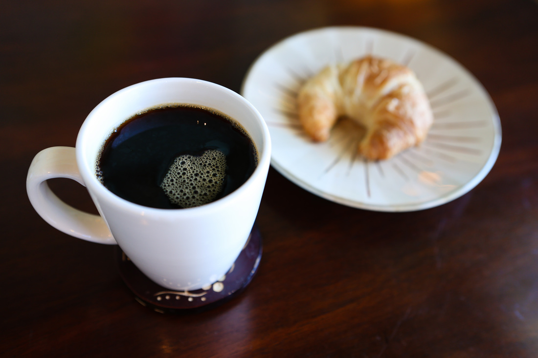 an image of a cup of coffee on a table with snacks by the side