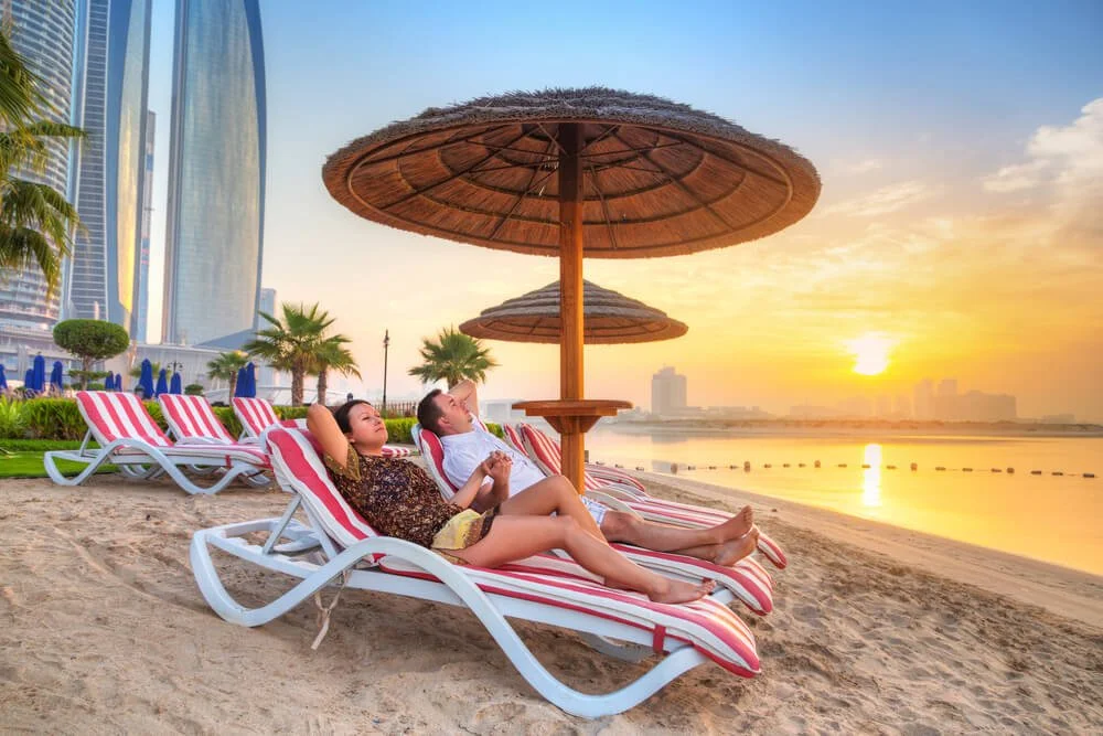 a man and a woman relaxing under a shade by the sea side